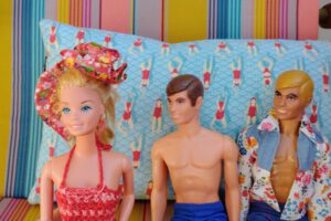 Zwei Kens schauen hinter einer Barbie her.