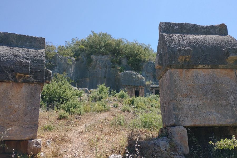 Felsengrab des Amyntos nahe Fethiye mit lykischen Steinsärgen im Vordergrund.