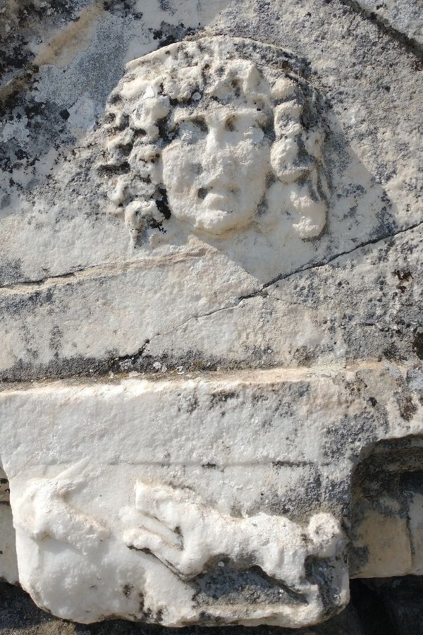 Detail eines Sarkophags mit Gesicht und Jagszene.