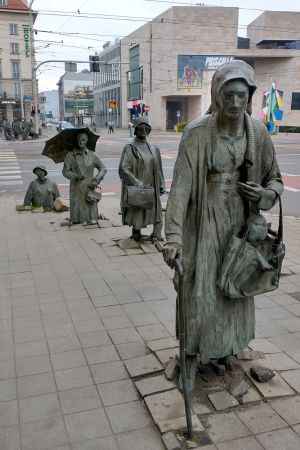 Auf der anderen Straßenseite steigen weitere sieben Skulpturen aus dem Boden heraus.