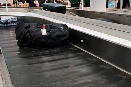 Rucksack mit Schutzsack auf dem Gepäckband am Flughafen.