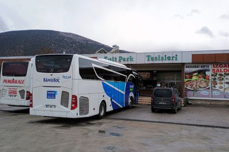 Zwei Reisebusse an einer Autobahnraststätte.