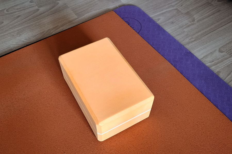 Ein Yogablock liegt auf einer Yogamatte.