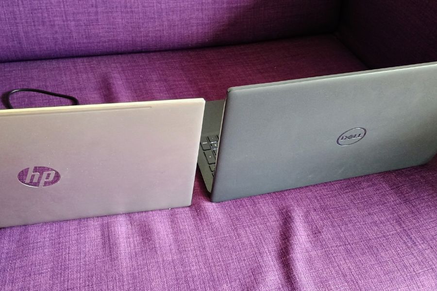 Zwei geöffnete Laptops stehen nebeneinander auf einem Sofa.