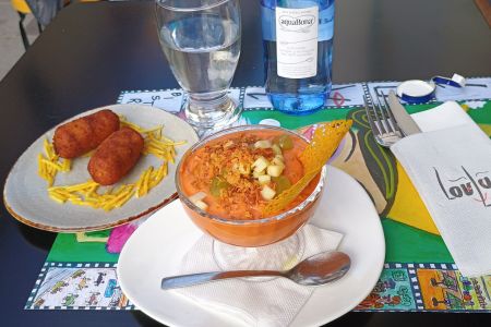 Auf einem Tisch im Loulu Bistro stehen ein kleiner Teller mit zwei Kroketten und eine kleine Schale mit der Suppe Porra de Antequera.