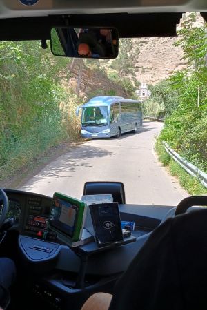 Zwei Reisebusse begegnen sich auf einer schmalen Straße.