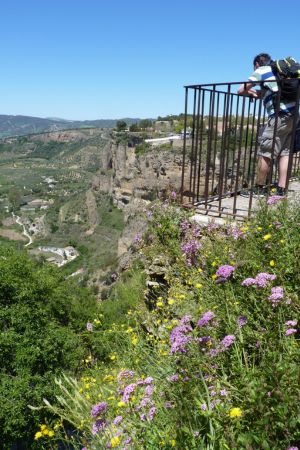 Ein Mann lehnt sich an das Geländer des Aussichtspunkts, um den Blick in die Umgebung von Ronda zu genießen.