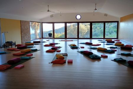 Yogamatten und Hilfsmittel im Yogastudio des Centro Santillan mit großer Fensterfront zum Meer.