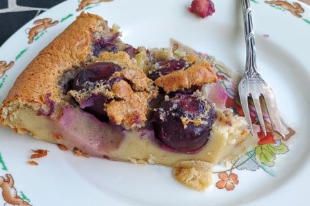 Ein Stück Clafoutis auf einem Teller mit silberner Kuchengabel.