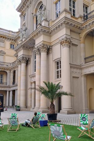 Liegestühle und eine Palme als Sommerdekoration, dahinter die restaurierte Fassade des Berliner Schlosses.