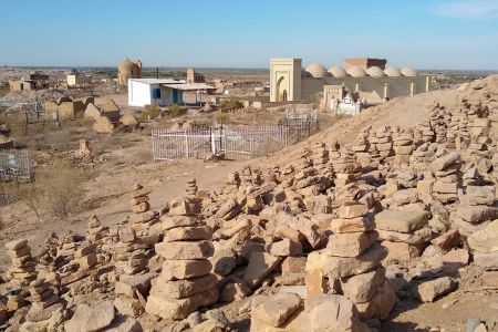 Stapel aus jeweils sieben Steinen in der Nekropole Mizdakhan, Usbekistan. Im Hintergrund das Mausoleum von Shamun Nabi.