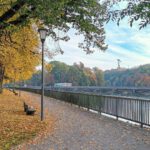 Gelbes Herbstlaub und Parkbänke am Isarkanal.