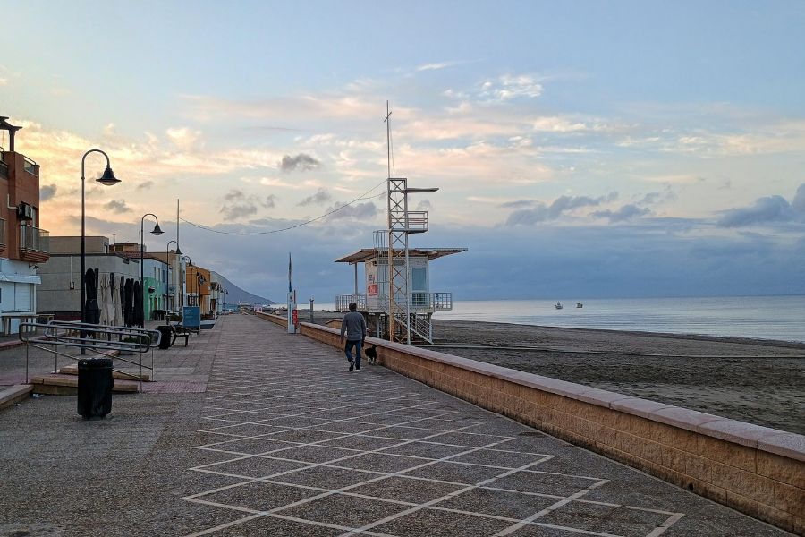 Ein Mann führt auf der leeren Strandpromenade von San Miguel, Cabo de Gata, seinen Hund Gassi.